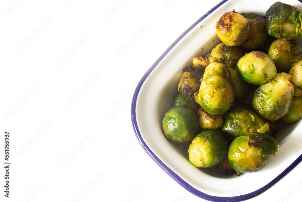 Brussels sprouts, oven roasted in olive oil,  in an enamel dish bowl. Isolated on a white background