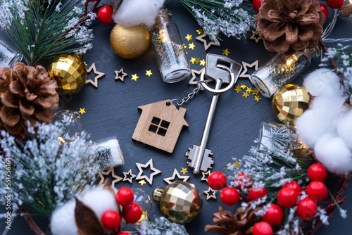 Key to the house with a keychain on black background with Christmas decor layout. A gift for New Year, Christmas. Building, design, project, moving to new house, mortgage, rent and purchase real estat photo