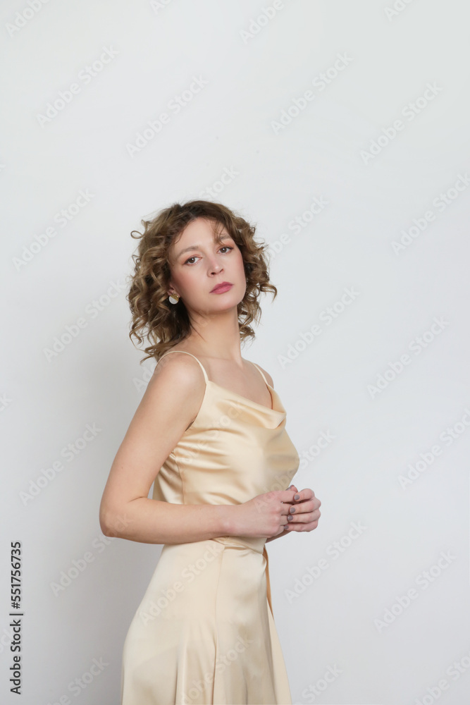 Female model wearing golden camisole silk top and wrapped midi skirt. Stylish monochrome summer outfit. Fashion Studio shot. Female model wearing golden camisole silk top and wrapped midi skirt. Stylish monochrome summer outfit. Fashion Studio shot.