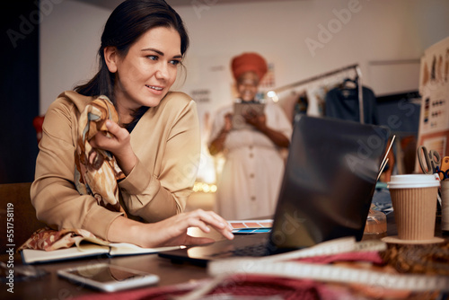 Woman, fashion designer and laptop planning, fabric ideas and internet technology in textile studio. Happy tailor, computer or manufacturing with team in startup, small business or creative workshop