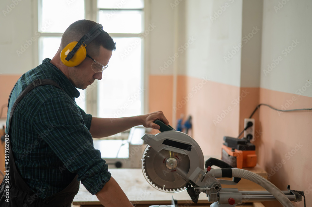 Master cuts the board with a circular saw in the workshop. 