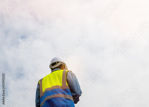 Rear view of positive worker in safety helmet against blue sky. Use as copy space, banner or background.