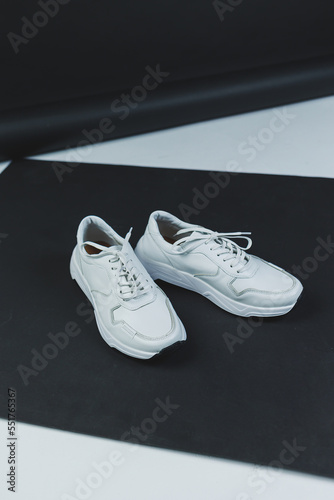 Men's white leather sneakers on a black background. Men's casual shoes