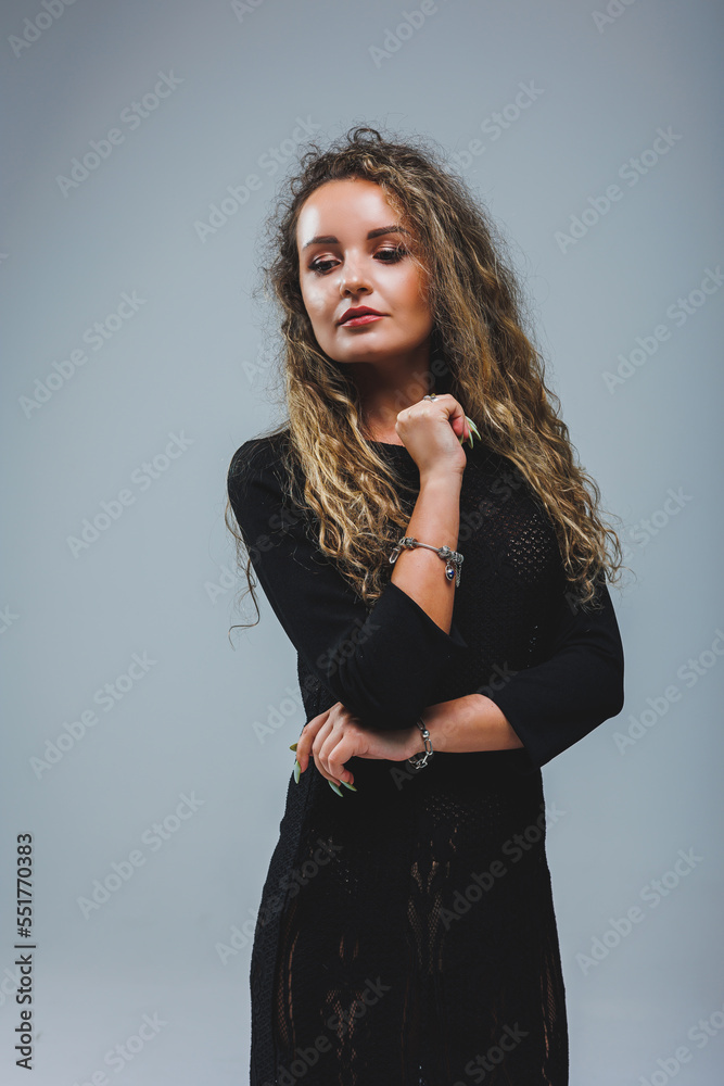 Young curly dreamy woman in black bodycon net dress standing on white background. Women's black dress Young curly dreamy woman in black bodycon net dress standing on white background. Women's black dress