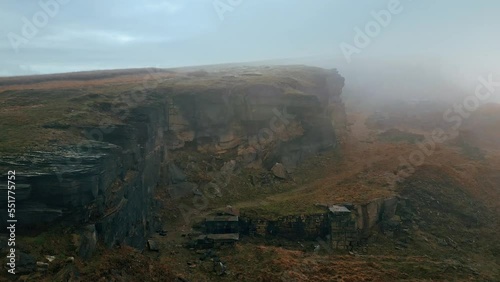 High up aerial view in the clouds, mist moving in over the cliff tops, foggy golden hills and beautiful rocky outcrop and moorlands. Flying above photo