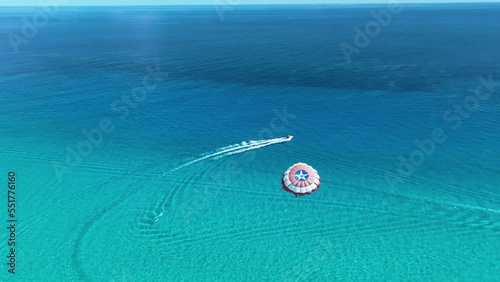 Aerial view following people parasailing on the coast of sunny Cancun, Mexico photo