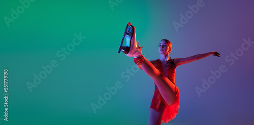 Winter sports. One junior female figure skater in red stage costume showing base figure skating elements, movements isolated over gradient green-blue background in neon light.