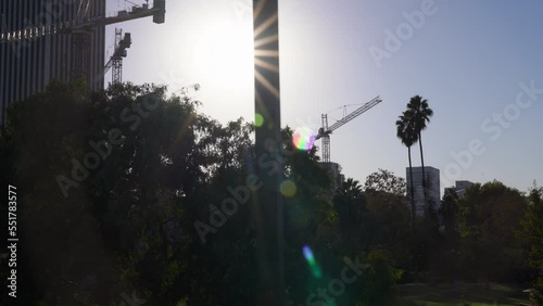 The camera tracks left revealing tall buildings just behind the Los Angeles County Museum of Art (LACMA) during sunset on a sunny California day. photo