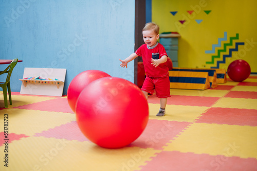 Happy laughing boy 1-2 years old having fun in ball pit  in kids amusement park and indoor play center. Activity toys for little kid photo