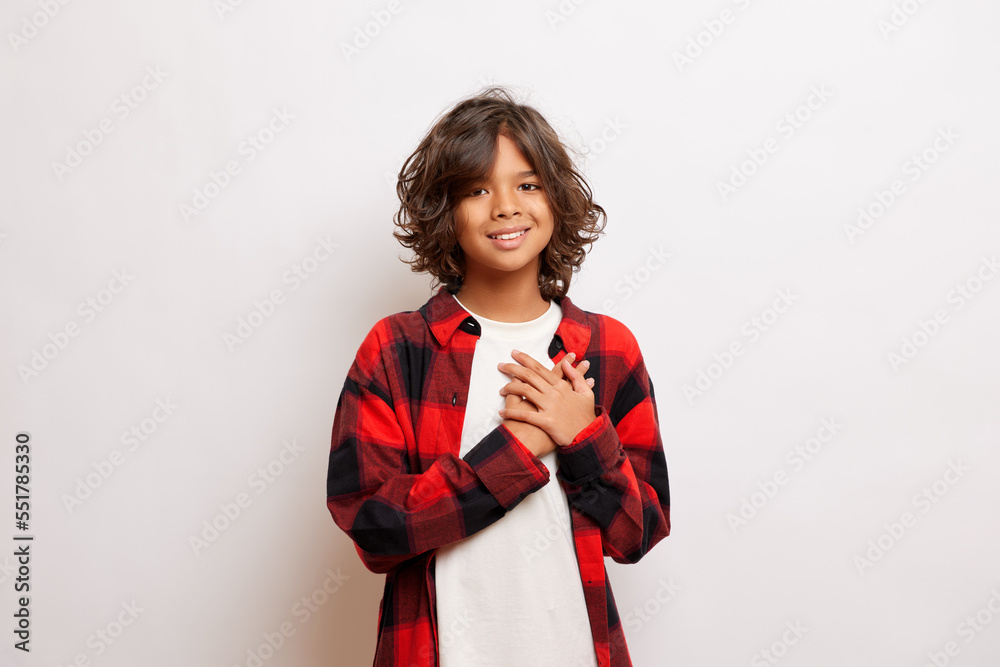 New Eve concept. Attractive teenager in Santa hat keeps hands over heart, smiles toothily, isolated over white background New Eve concept. Attractive teenager in Santa hat keeps hands over heart, smiles toothily, isolated over white background