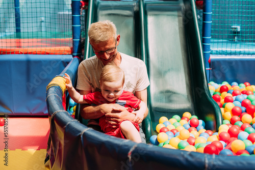 Happy laughing boy 1-2 years old having fun in ball pit  in kids amusement park and indoor play center. Activity toys for little kid
