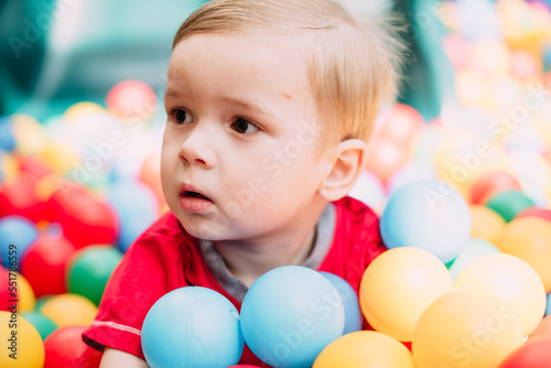 Happy laughing boy 1-2 years old having fun in ball pit  in kids amusement park and indoor play center. Activity toys for little kid
