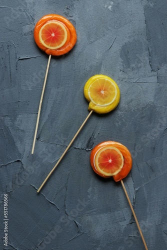 Lollipop with lemon and orange on a grey background
