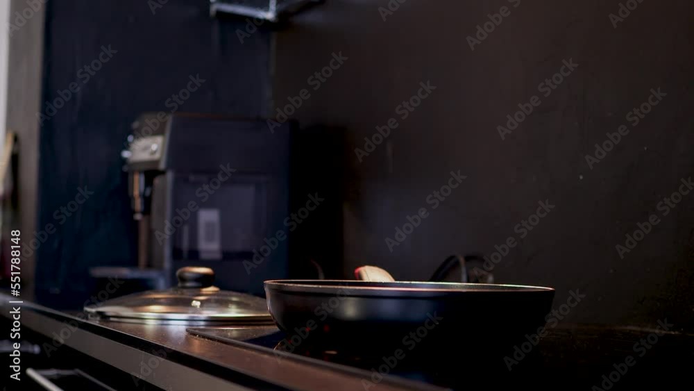 A woman in an apron cooks at home in the kitchen. Frying champignons in a frying pan, close-up A woman in an apron cooks at home in the kitchen. Frying champignons in a frying pan, close-up
