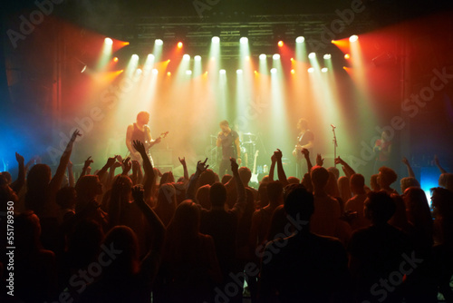 Rock  band and crowd of people at concert for stage performance  party dance and new year or holiday festival in dark. Dancing  singing and celebrity or musician with night club music for an audience