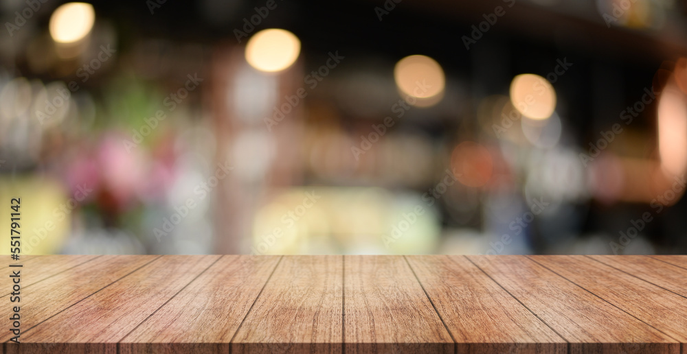 Empty wooden table top with lights bokeh on blur restaurant background.