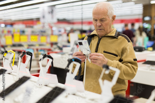 senor man pensioner buying modern tablet digital in showroom of digital electronic goods store