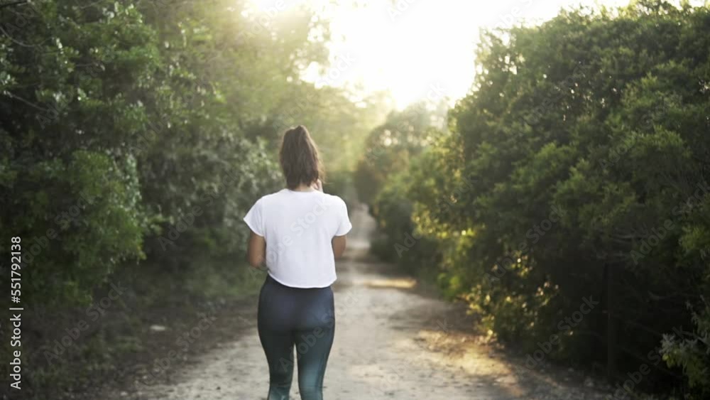 model in athletic gym wear walking along a rural hiking route
