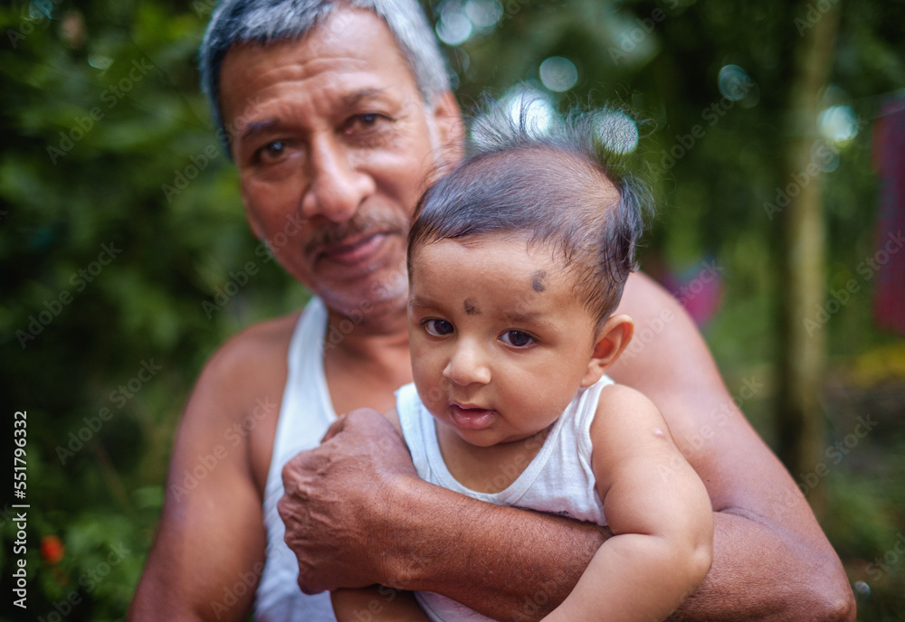close up portrait of south asian aged grandfather holding his grandson in a green village environment close up portrait of south asian aged grandfather holding his grandson in a green village environment