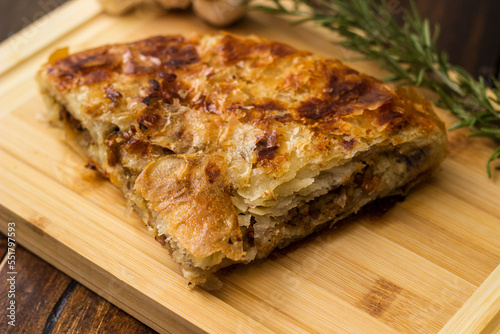Tasty pie baked with meat with garlic and rosemary. On cutting board