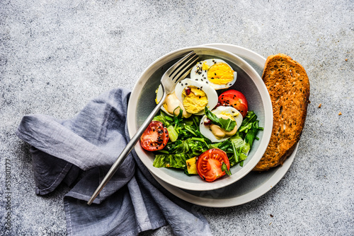 Overhead view of a salad with hard boiled eggs, avocado, tomato, lettuce and a slice of toast