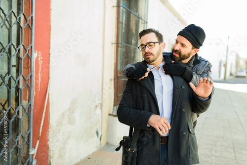 Homeless robber mugging a young man with a knife to buy food