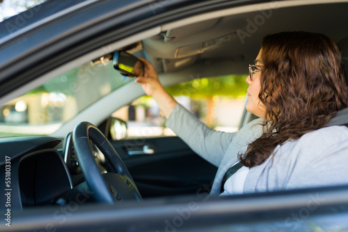 Side view of a big woman checking the car rearview mirror