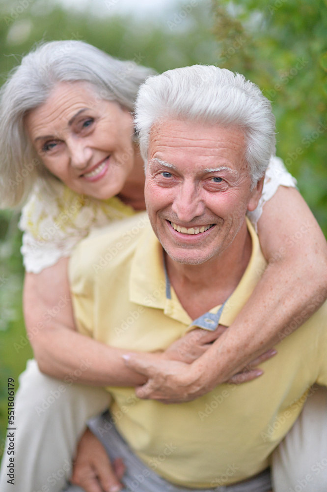 elderly man holding an old woman on his back in summer