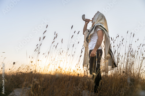 Obraz na plátne Jewish man in a traditional tallit prayer shawl blowing the ram's horn shofar, i