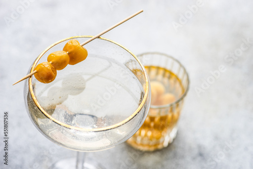 Close-up of a vodka cocktail and a tumbler filled with yellow glace cherries photo