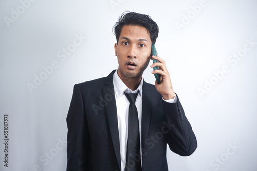 Young Asian Man is confused and shocked when calling in the phone. Indonesian man wearing a black shirt.