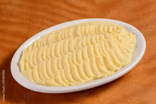 Mashed potatoes. Small portion in white bowl on wooden background.