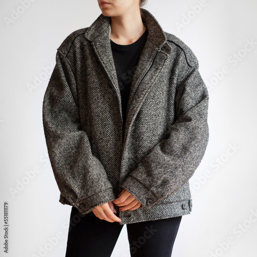 Woman wearing oversized woolen jacket, black jeans and black top isolated on white background
