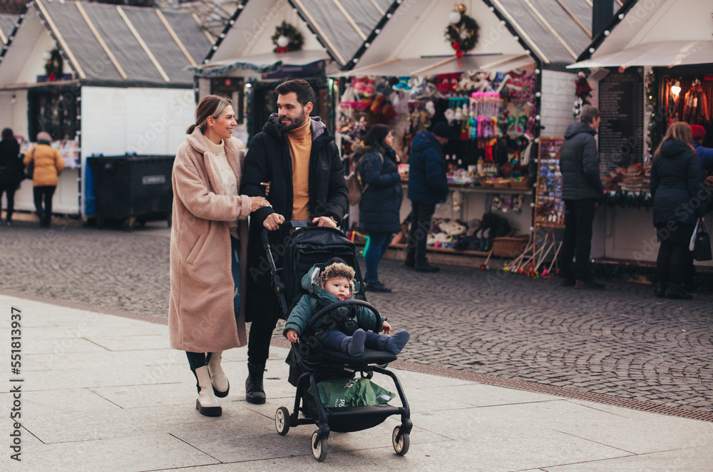 Obraz premium family on a walk with a baby in a stroller through the Christmas market