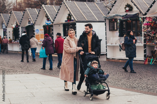 family on a walk with a baby in a stroller through the Christmas market