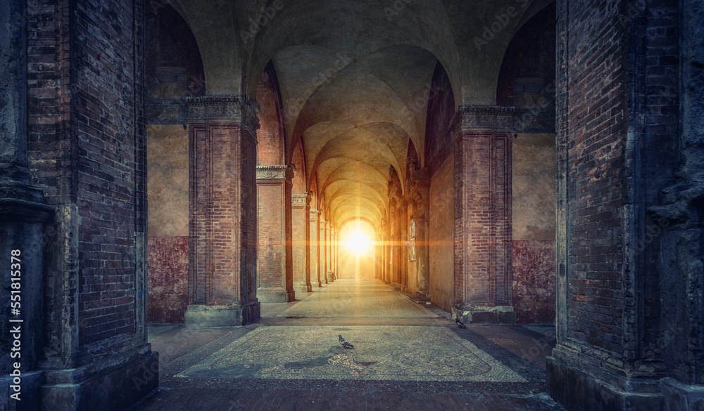 Fototapeta premium Rays of divine light illuminate old arches and columns of ancient buildings. Bologna, Italy. Conceptual image on historical, religious and travel theme.