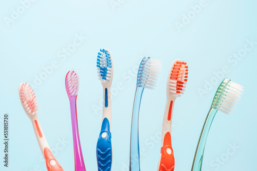 Multi-colored toothbrushes on blue background, copy space.