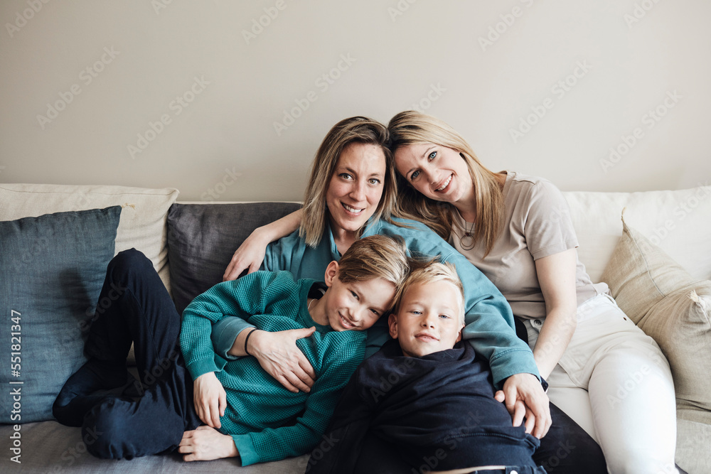 Portrait of lesbian mothers with sons sitting together on sofa at home Portrait of lesbian mothers with sons sitting together on sofa at home