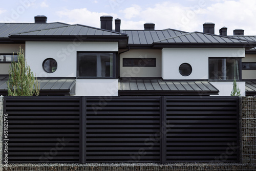 New cottages with a metal black fence on a blue sky background