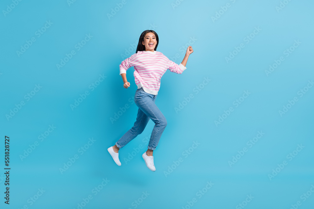 Full length photo of excited pretty girl dressed pink pullover jumping high running fast isolated blue color background