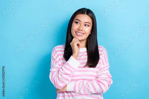 Photo of young attractive japanese lady smiling cheerful touch chin looking empty space good news from politics isolated on blue color background