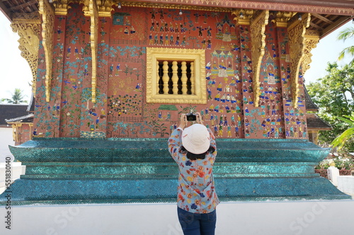 Asian tourists used their digital cameras to capture the beauty of the golden windows and exterior walls in Wat Xieng Thong   Wall  Buddhist temple in Luang Prabang  Laos.  