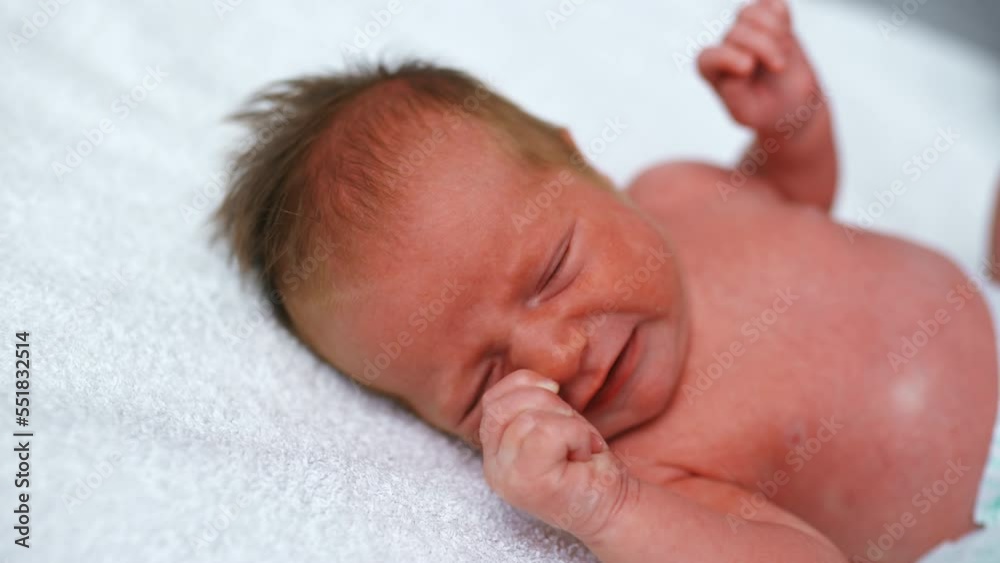 Newborn caucasian infant baby boy with his yet slightly red skin lying down on soft white blanket during diaper changing. Closeup shot. High quality 4k footage Newborn caucasian infant baby boy with his yet slightly red skin lying down on soft white blanket during diaper changing. Closeup shot. High quality 4k footage