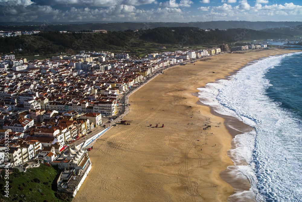 Top view of Nazare beaches and Nazare city and ocean. Traditional urban buildings and mountains in the background
