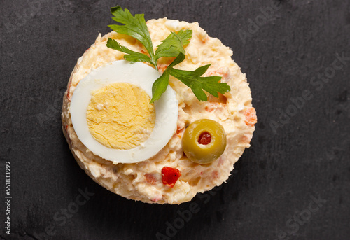 Top view of russian salad  on a black slate plate. Typical spanish tapa