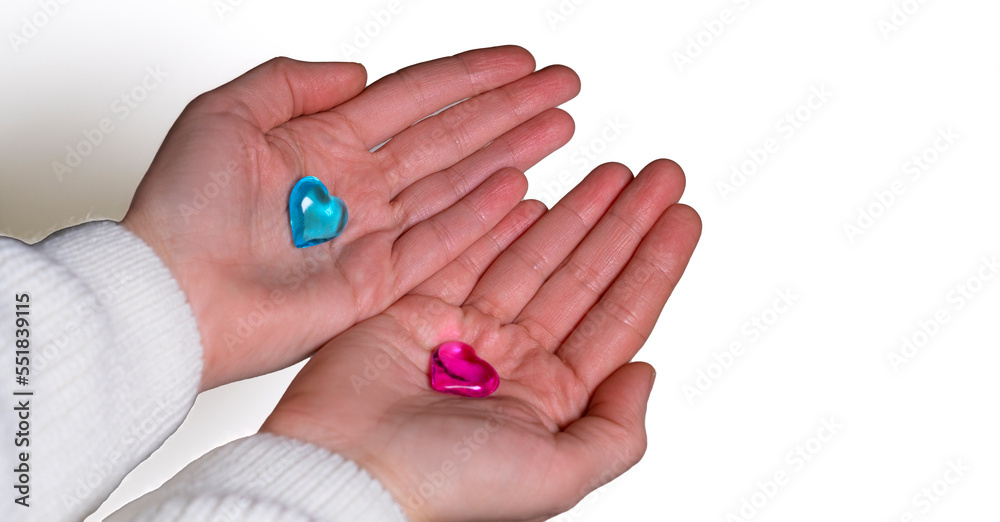 female hands on a white background hold glass hearts blue and pink female hands on a white background hold glass hearts blue and pink