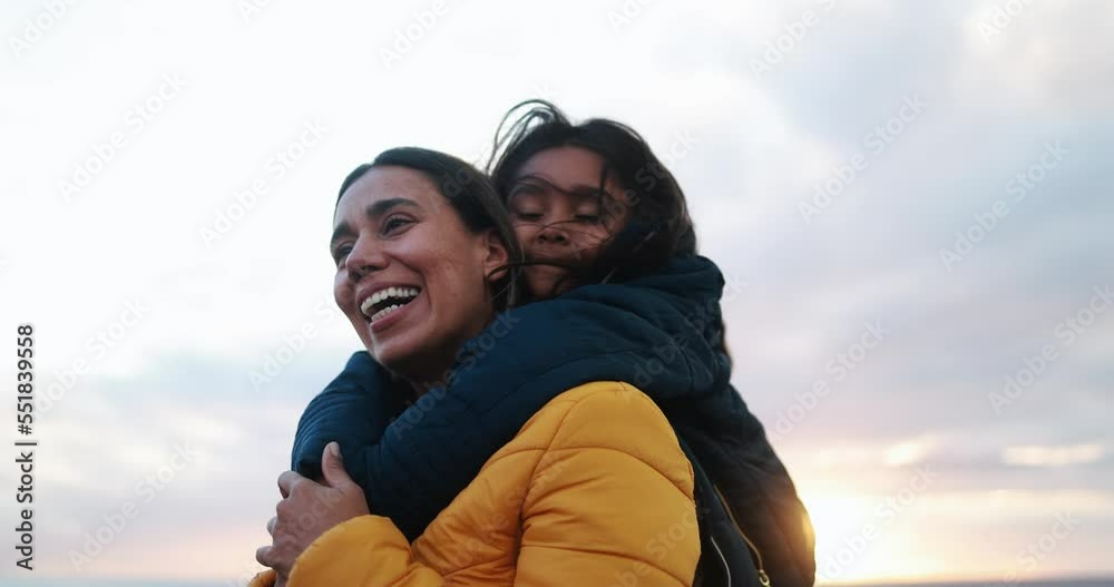Latin girl hugging her mother on the beach at sunset during winter time Latin girl hugging her mother on the beach at sunset during winter time