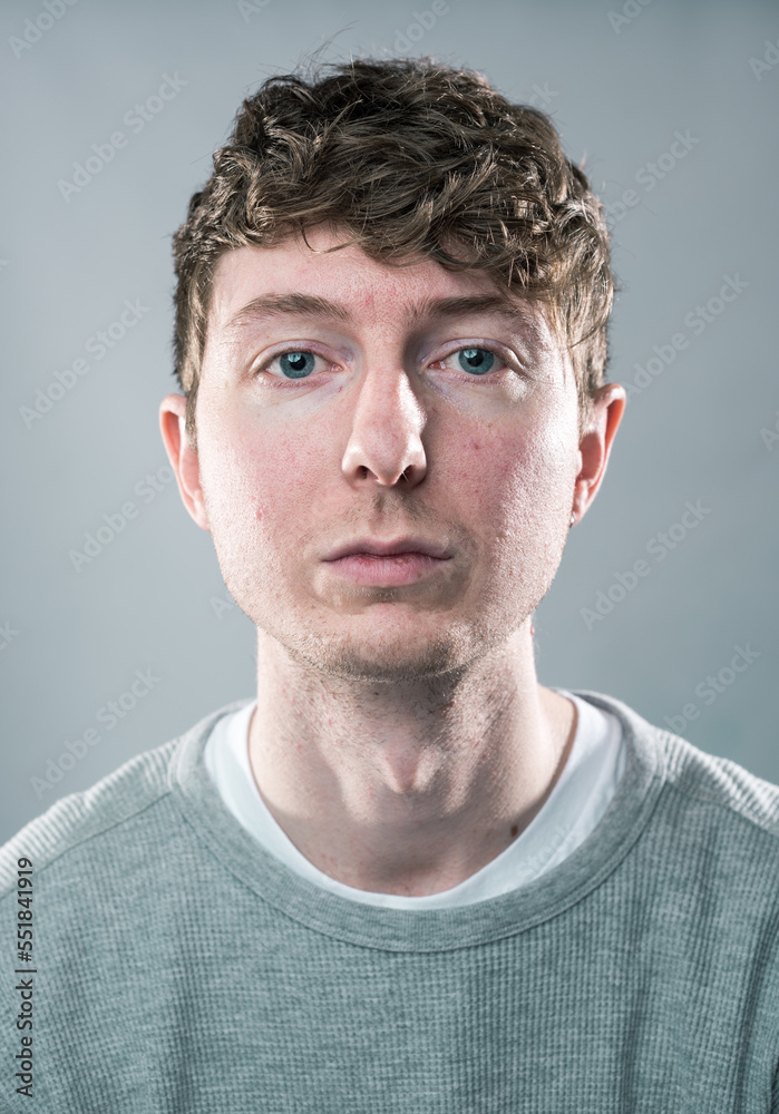 Obraz premium A young trendy stylish handsome male staring straight into the camera. A Young hipster student thinking and pondering about life and the future after graduation. No expression staring ahead.