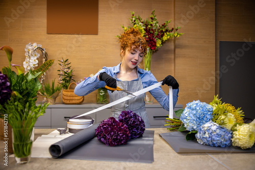 Cute ginger florist looking involved while making a cover for the bouquet photo