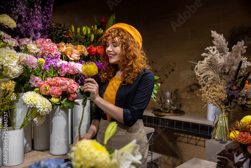 Cute florist in a flower shop looking enjoyed photo